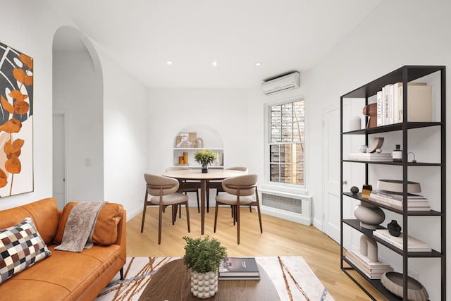 dining space featuring arched walkways, light wood-style flooring, recessed lighting, baseboards, and a wall unit AC