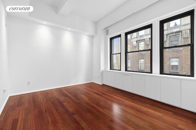 unfurnished room featuring visible vents, beamed ceiling, baseboards, and wood-type flooring