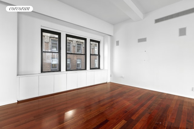 unfurnished room featuring hardwood / wood-style floors, beam ceiling, and visible vents