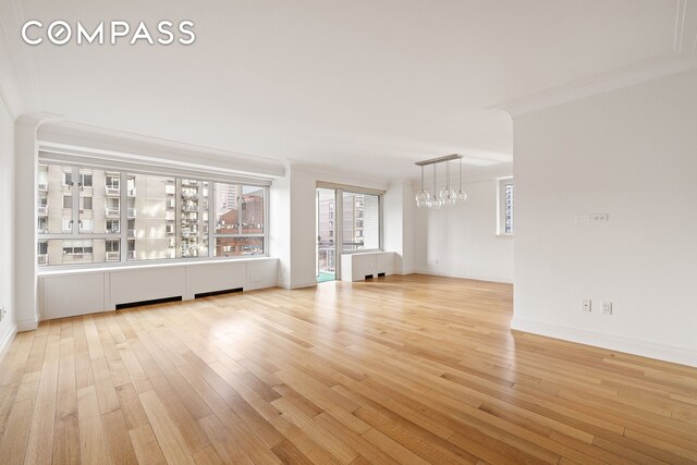 200 E 66th St Unit D1203, New York City, NY 10065 - unfurnished living room with a chandelier, light wood-type flooring, and baseboards