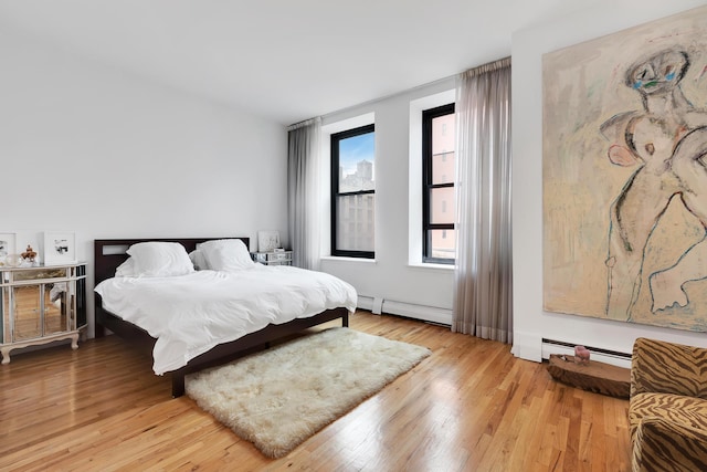 bedroom featuring a baseboard heating unit, a baseboard radiator, and light wood-style flooring