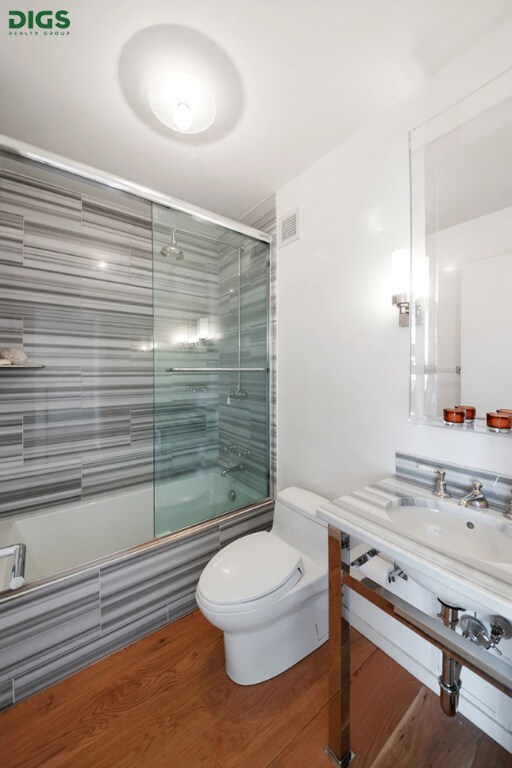 bathroom featuring toilet, vanity, and a shower with door