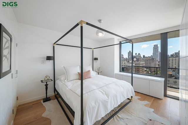 bedroom with baseboards, a view of city, and light wood finished floors