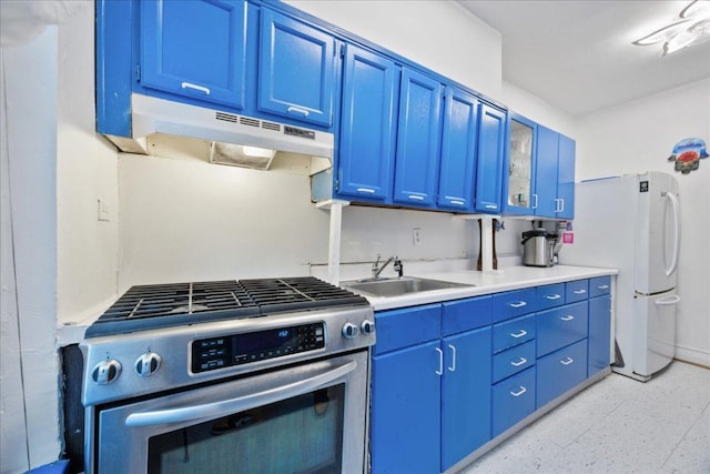 kitchen featuring sink, blue cabinetry, white fridge, and gas range