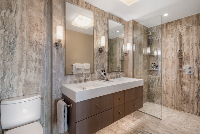 bathroom with tile walls, toilet, vanity, and a tile shower