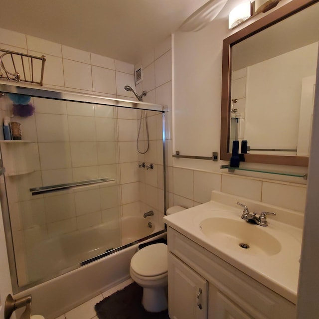 full bath featuring vanity, visible vents, tile walls, toilet, and combined bath / shower with glass door