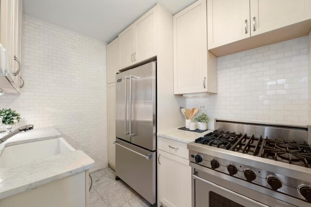 kitchen featuring sink, light stone counters, stainless steel appliances, and white cabinetry