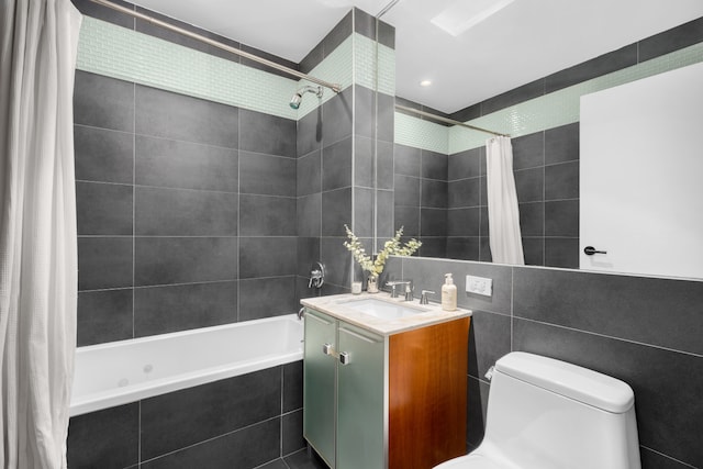 full bath featuring toilet, tiled shower / bath combo, vanity, and tile walls