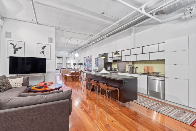 living room with a towering ceiling, track lighting, and light wood-type flooring