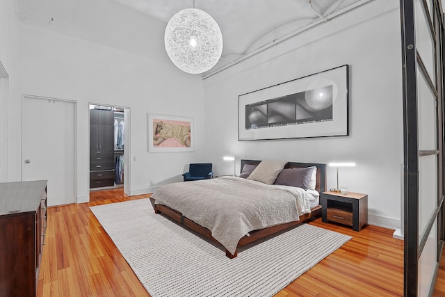 bedroom with light hardwood / wood-style flooring and a high ceiling