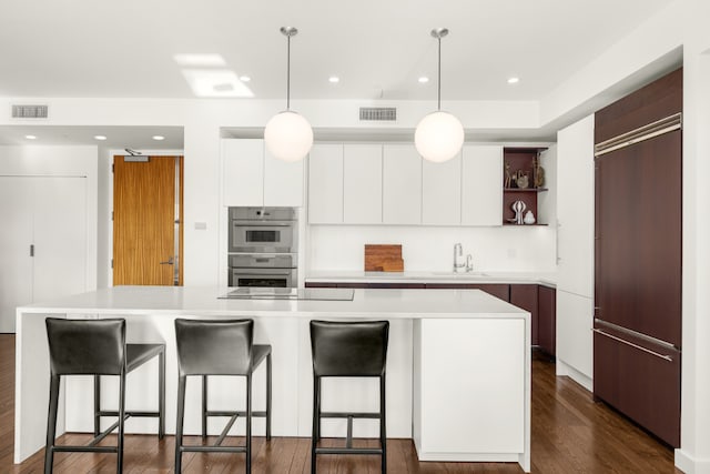 kitchen with a kitchen island, double oven, white cabinetry, sink, and black electric stovetop