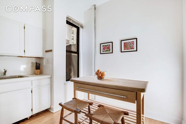 interior space featuring sink, light hardwood / wood-style floors, and white cabinets