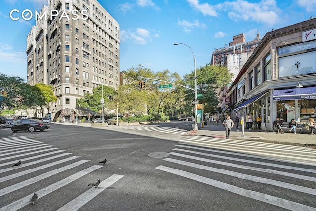 view of asphalt road featuring street lights, sidewalks, and curbs
