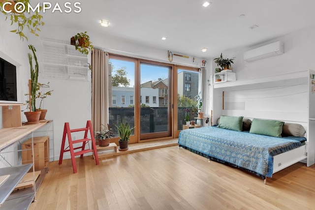 bedroom with hardwood / wood-style floors, access to outside, and a wall mounted AC