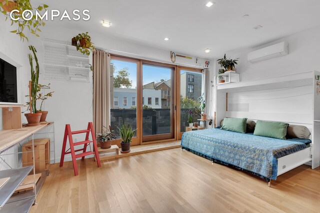 bedroom with recessed lighting, wood finished floors, and a wall unit AC