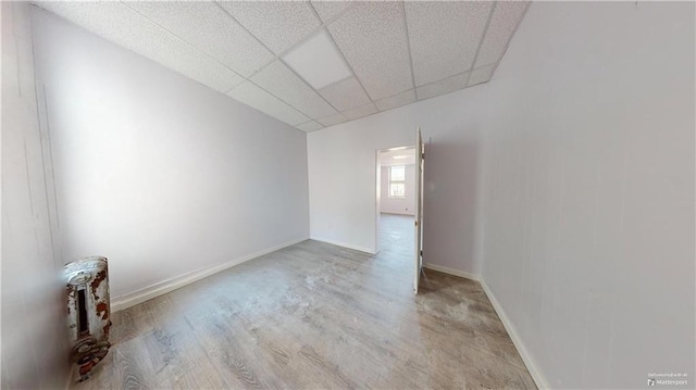 empty room featuring light wood-type flooring and a paneled ceiling