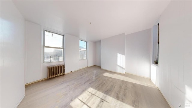 unfurnished room featuring radiator and light wood-type flooring