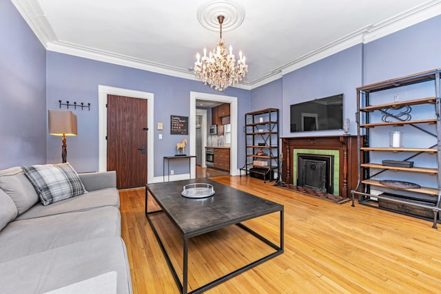 living room featuring a fireplace, ornamental molding, wood finished floors, a chandelier, and baseboards