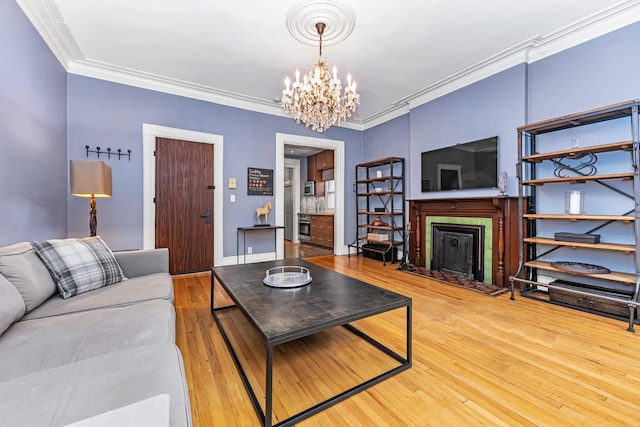 living room with baseboards, a chandelier, ornamental molding, a fireplace, and wood finished floors