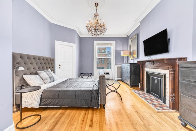 bedroom with light wood-type flooring, a notable chandelier, a fireplace, and crown molding