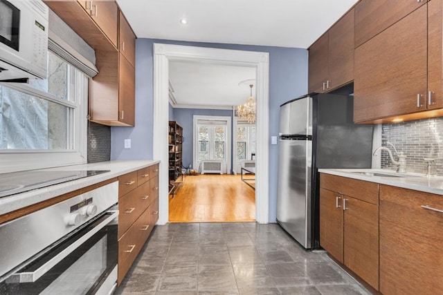 kitchen featuring a notable chandelier, appliances with stainless steel finishes, decorative backsplash, and sink