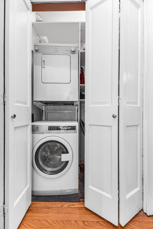 laundry room featuring stacked washing maching and dryer and light wood-type flooring