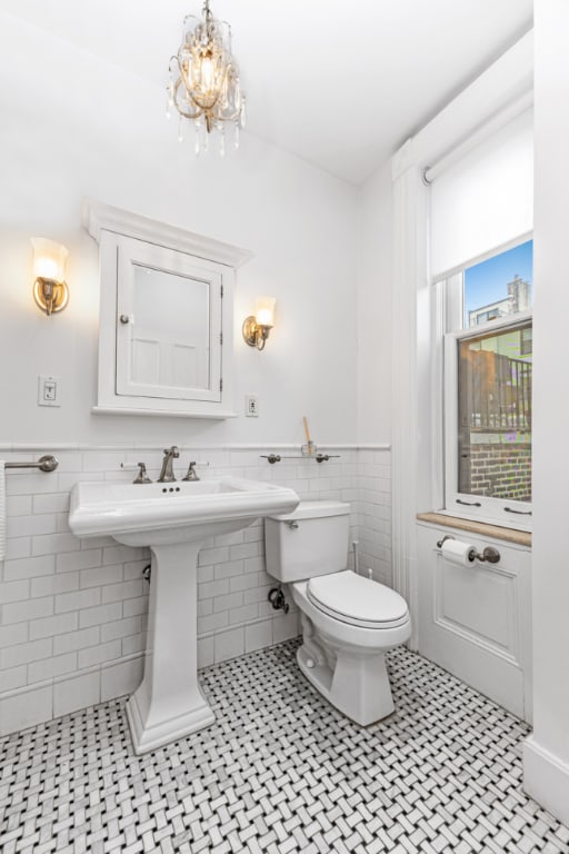 bathroom featuring toilet, tile walls, a notable chandelier, and tile patterned floors