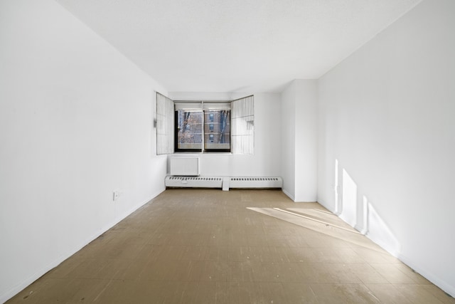 unfurnished room featuring a baseboard heating unit and tile patterned floors