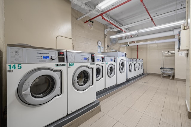 common laundry area with washer and clothes dryer and concrete block wall