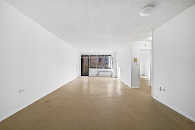 unfurnished living room with radiator heating unit and a textured ceiling