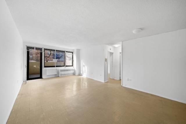 empty room with radiator and a textured ceiling