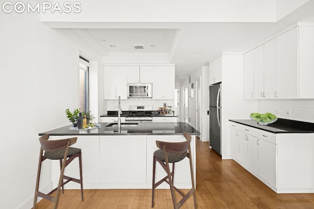 kitchen featuring white cabinets, kitchen peninsula, a kitchen breakfast bar, and stainless steel appliances