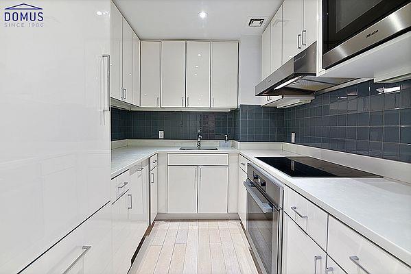 kitchen featuring white fridge, white cabinets, black electric stovetop, a sink, and oven