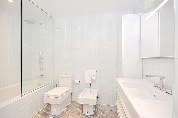 bathroom with toilet, a bidet, tiled shower / bath combo, and tile walls