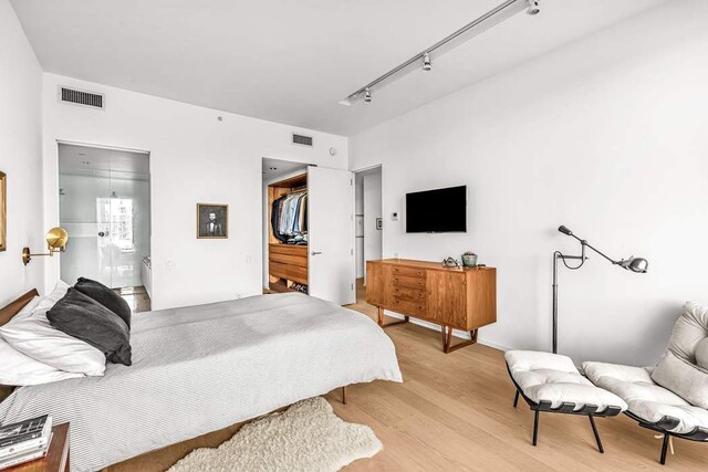 bedroom featuring access to exterior, a water view, and light wood-type flooring