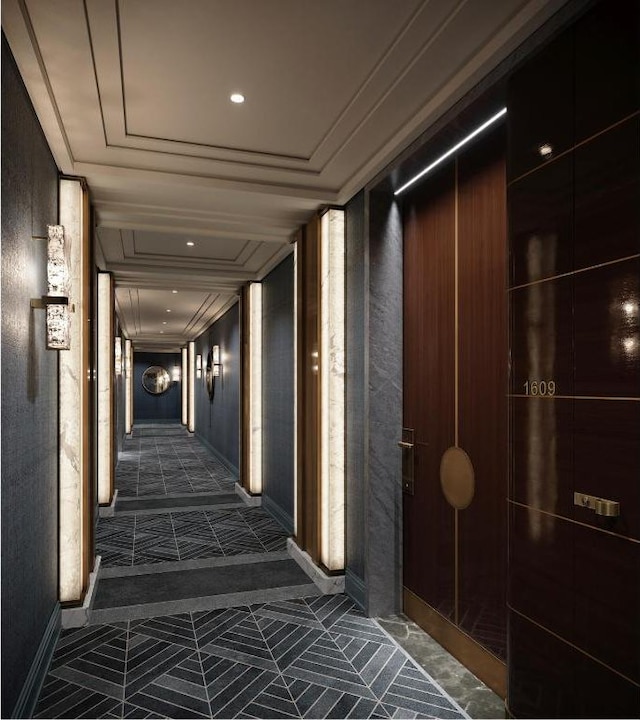 corridor with ornamental molding, a raised ceiling, and dark tile patterned flooring