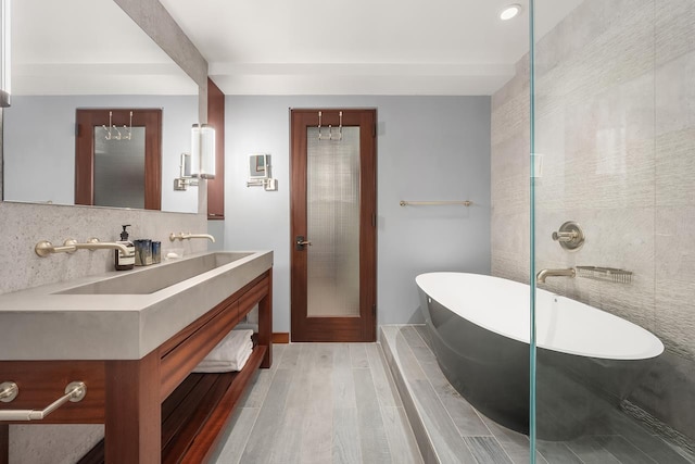 bathroom with vanity, a freestanding bath, tasteful backsplash, and wood finished floors