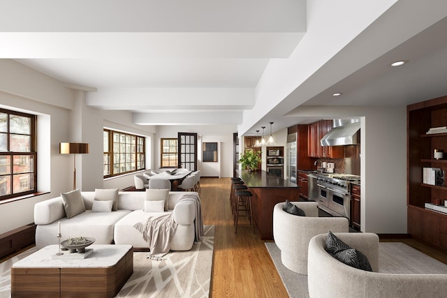 living area featuring recessed lighting, beamed ceiling, and light wood-type flooring