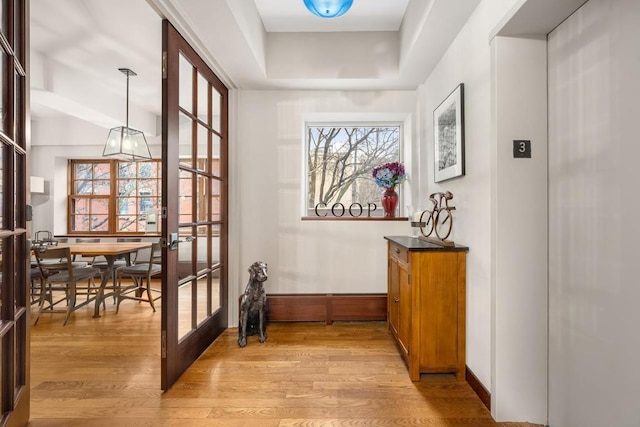 doorway to outside with french doors, light wood-style flooring, and baseboards