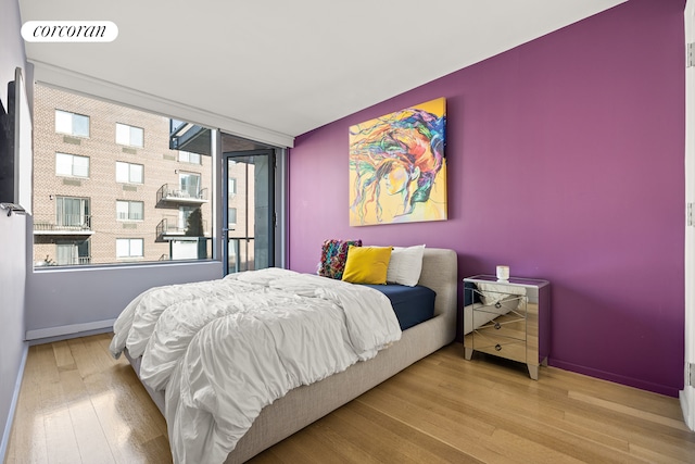 bedroom with baseboards, visible vents, and wood finished floors