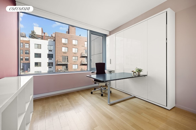 office featuring light wood-style floors, a view of city, and baseboards