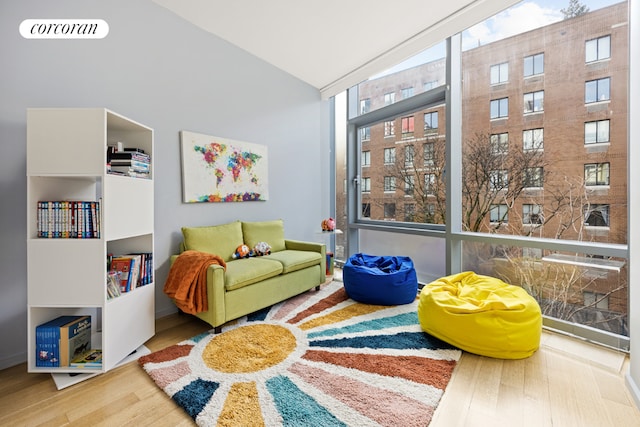 recreation room featuring lofted ceiling, a wall of windows, and hardwood / wood-style flooring