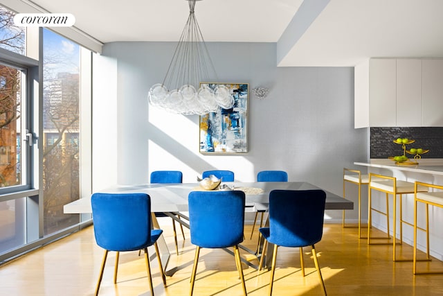 dining space with floor to ceiling windows, light hardwood / wood-style flooring, and an inviting chandelier