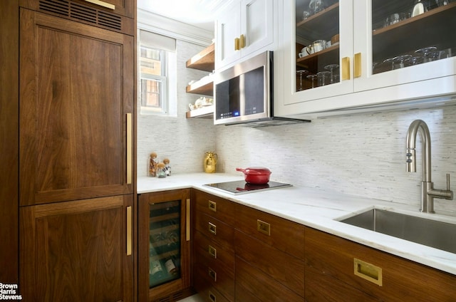 bar with wine cooler, stainless steel microwave, decorative backsplash, a sink, and paneled built in refrigerator