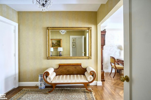 living area featuring a notable chandelier, baseboards, and parquet flooring