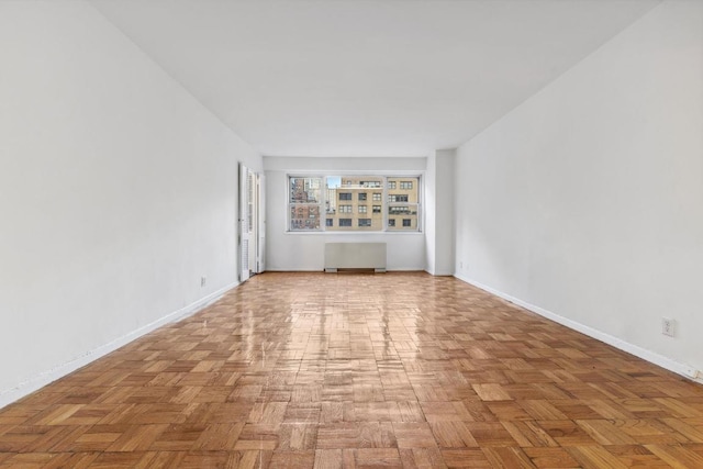 unfurnished living room with radiator and light parquet flooring