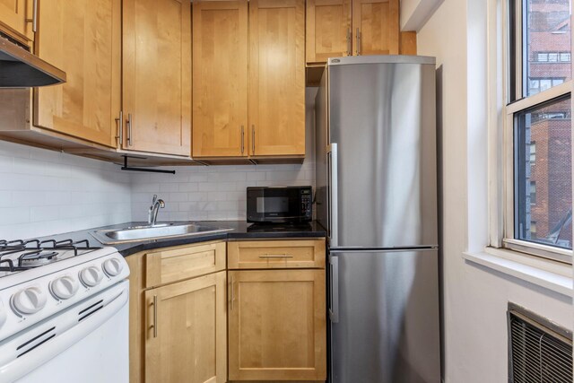 kitchen featuring ventilation hood, black microwave, white gas range oven, freestanding refrigerator, and a sink