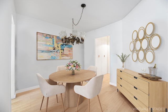 dining space with a chandelier, baseboards, and light wood finished floors