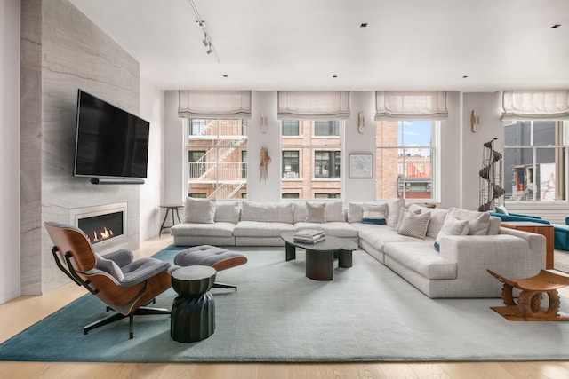 living area with a large fireplace, track lighting, and wood finished floors