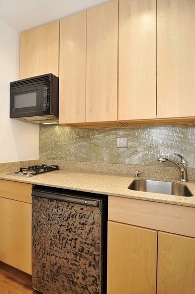 kitchen featuring light brown cabinetry, sink, and black appliances